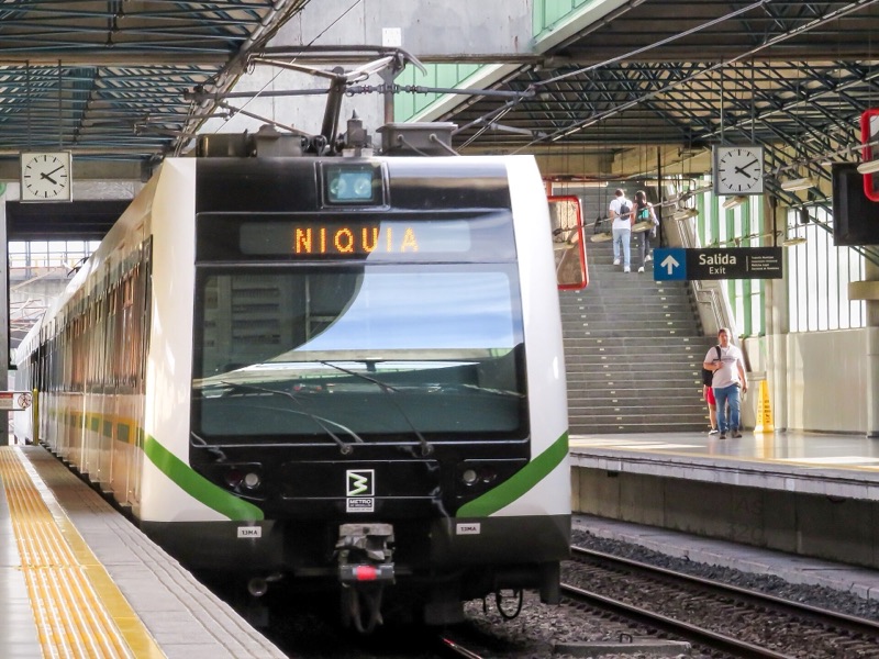A white and green Metro de Medellín train bound for Niquía waiting at a station platform