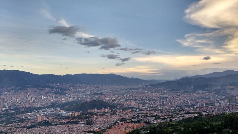 Medellín spread across the Aburrá Valley at dusk, with mountains on both sides, seen from Cerro El Picacho