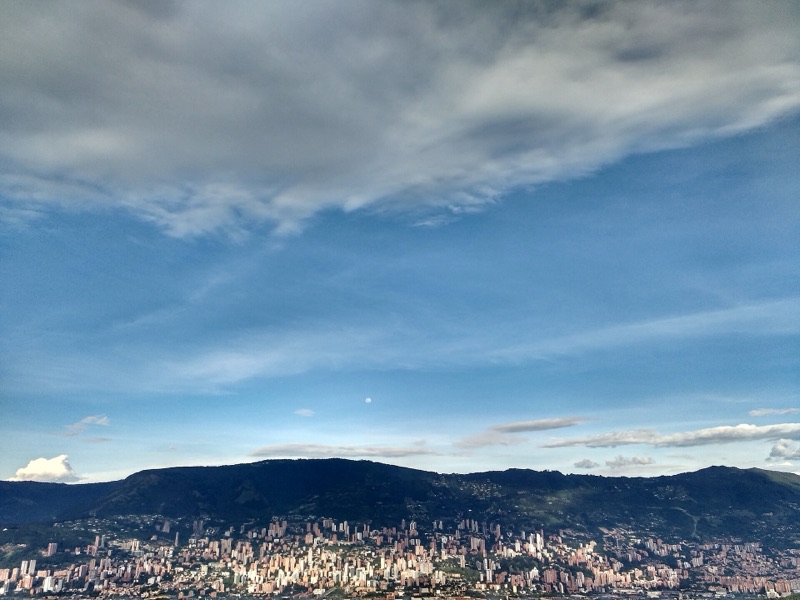 Big clouds and blue sky over the green mountains and apartment towers of southern Medellín